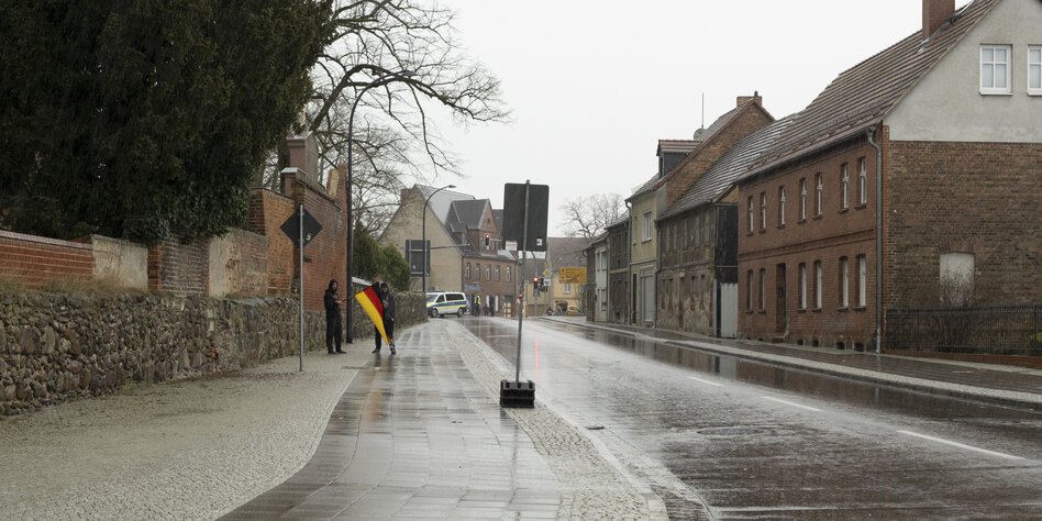 Zwei Menschen mit Deutschlandfahne auf sonst menschenleerer Straße in Jüterbog